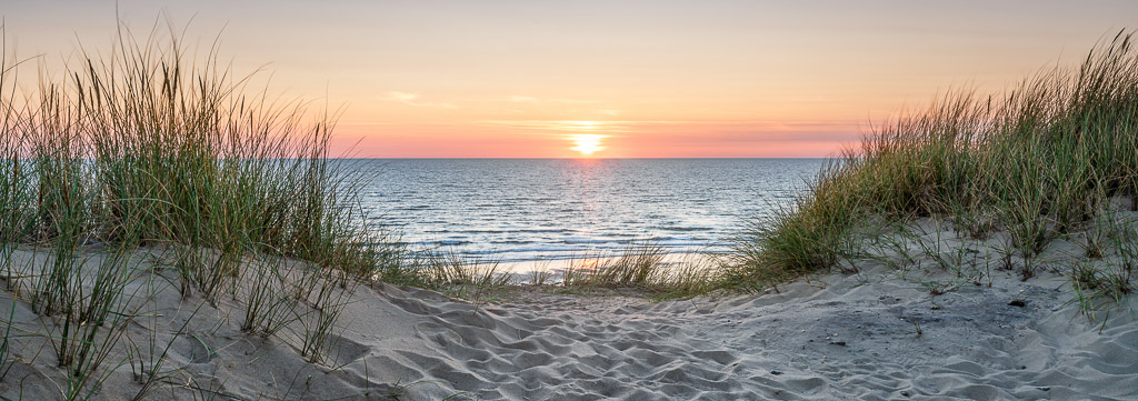 ondergaande zon in zee achter de duinen