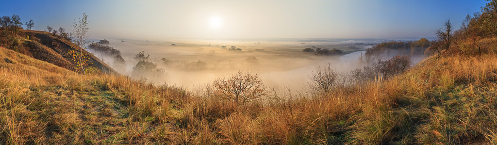 uitzicht van een heuvel op een rivier met flarden mist